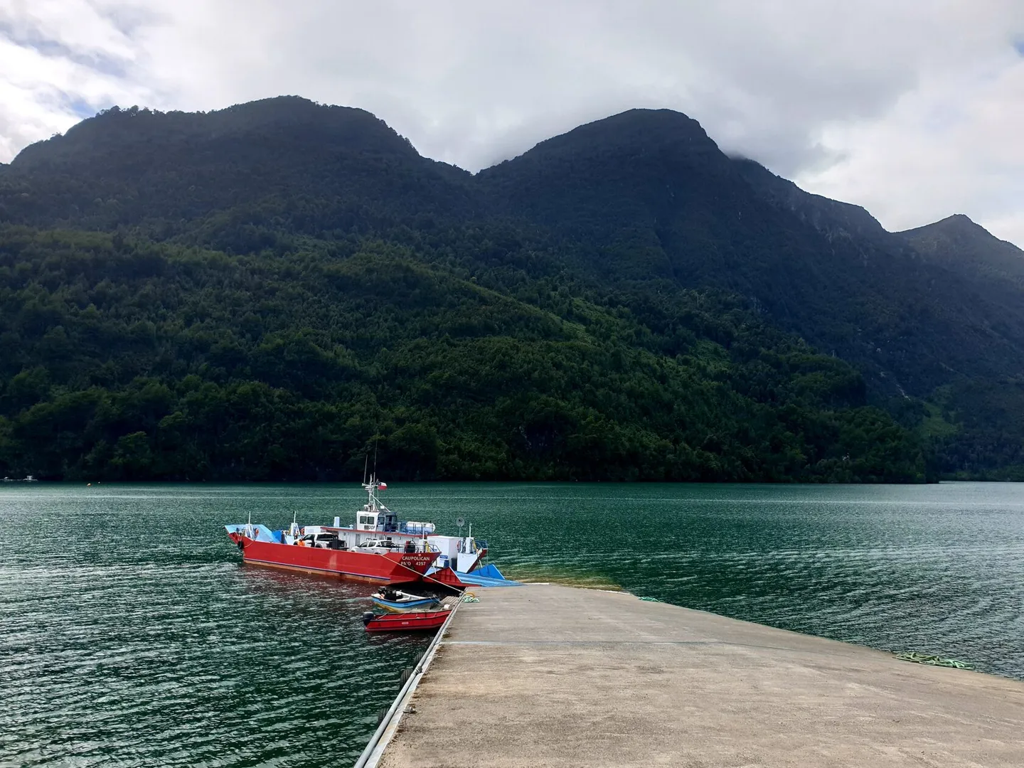 Лодка у причала под лесистыми горами