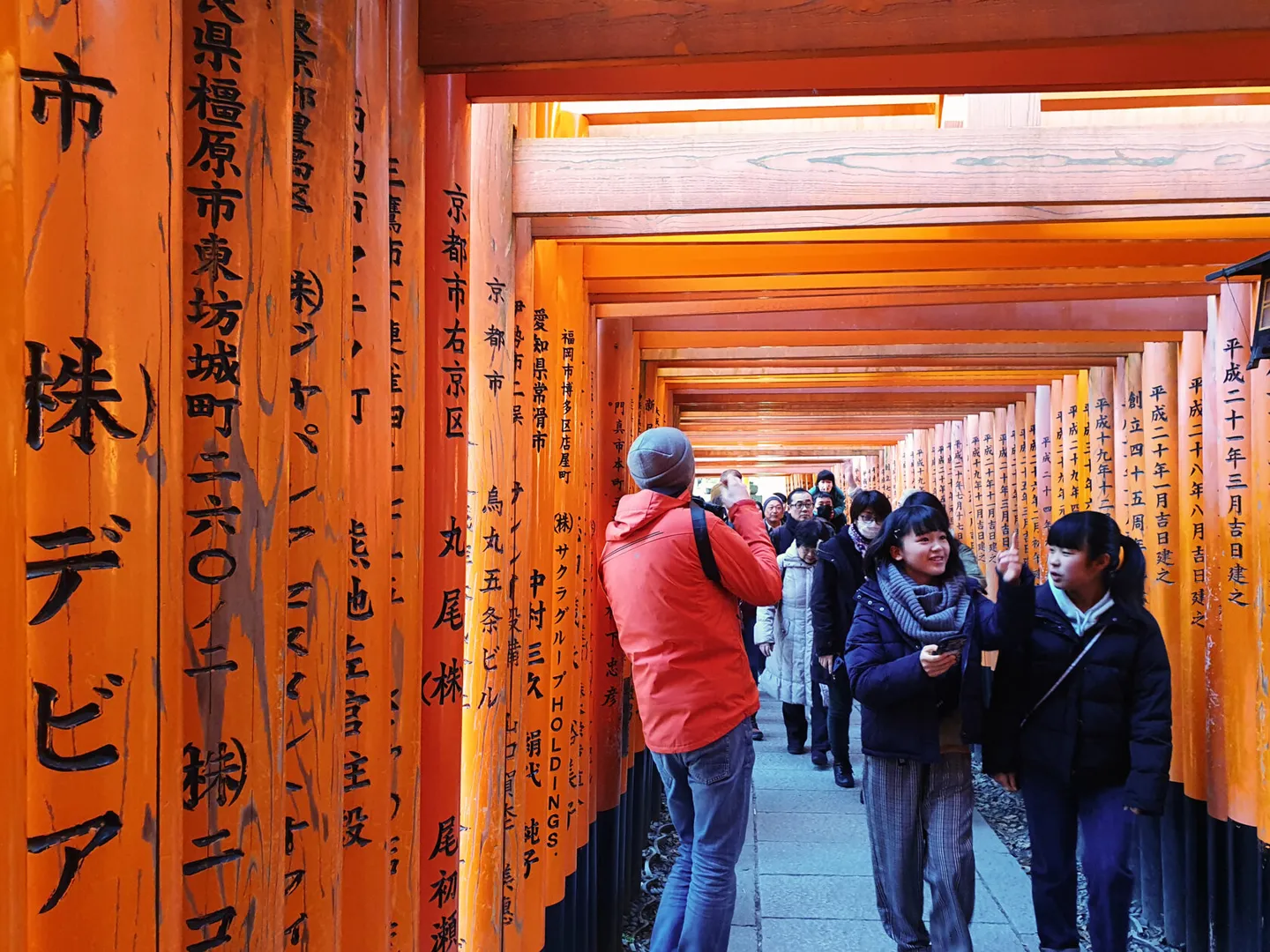 Visitors walking through the red torii gates at Fushimi Inari